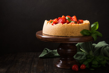 Dark photo of delicious homemade strawberry cheesecake decorated with basil leaves on old wooden background. Selective focus. Copy space.
