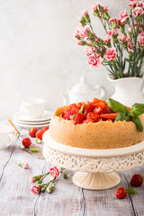 Delicious homemade strawberry cheesecake and flowers on old white wooden background. Selective focus. Copy space.