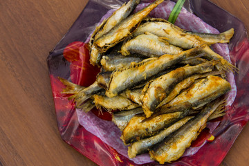 Fried baltic herring on a plate on wooden background
