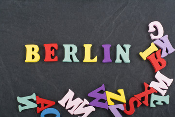 BERLIN word on black board background composed from colorful abc alphabet block wooden letters, copy space for ad text. Learning english concept.