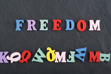 FREEDOM word on black board background composed from colorful abc alphabet block wooden letters, copy space for ad text. Learning english concept.