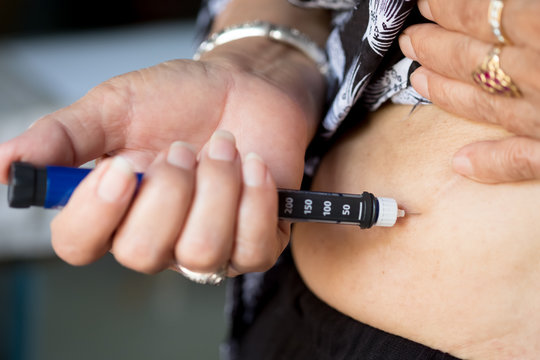 close up of old woman hands making injection with insulin pen or syringe, medicine, diabetes, glycemia, health care and people concept .