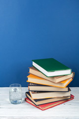 Book stacking. Open book, hardback books on wooden table and gblue background. Back to school. Copy space for text.