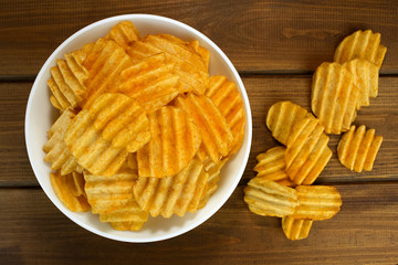 Potato chips in bowl on a wooden background, top view