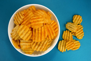 Potato chips on a blue background, top view