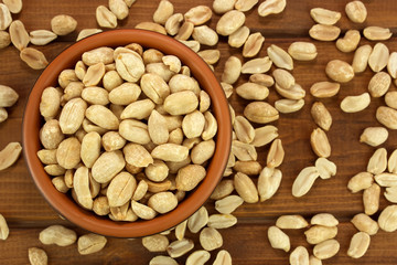 Roasted salted peanuts in bowl on a wooden background