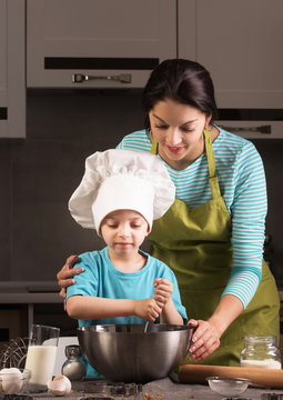 Happy family in the kitchen. Mother and son in chef hat.