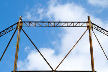 Old rusted metal structure over blue sky with clouds