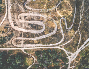 rolled tracks in countryside terrain with grove, top view, aerial photo