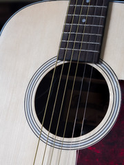 Close up shot of acoustic guitar. Strings, sound hole , bridge, pickguard