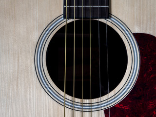 Close up shot of acoustic guitar. Strings, sound hole , bridge, pickguard