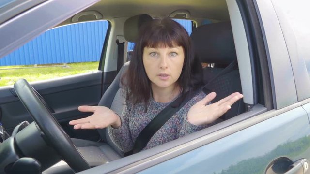 Young angry woman in perplexity sitting in the car.