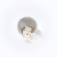 Fototapeta na wymiar White cup with sugar cubes on white background