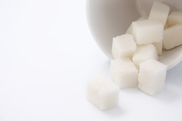 White cup with sugar cubes on white background