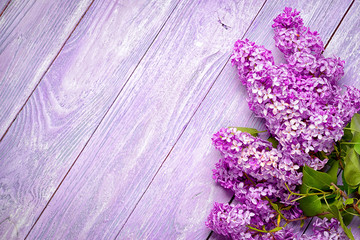 A bunch of lilacs at the corner of the wooden plank table with copy space