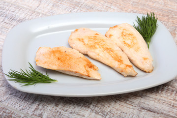 Slices of roasted chicken breast and tomato on white plate