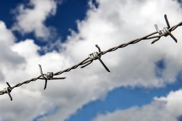 The barbed wire close up. Drawn wire fence under the blue sky.