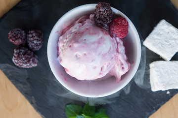 The white-pink ice cream top with berries and steam on the slate
