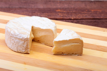 Cheese with white mold. Camembert or brie type on wood table. Healthy breakfast.