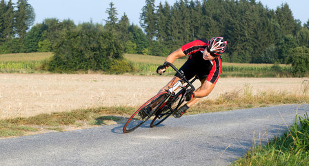 Cyclist riding a bike at extreme angle. Biker in a curve in the road. Fast driving on a road bike...