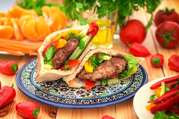 Pita bread with fried pork chop and vegetable, olive, spring picnic. Wooden background. Close-up. Top view