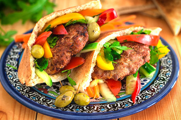 Pita bread with fried pork chop and vegetable, olive, spring picnic. Wooden background. Close-up. Top view