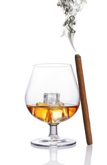 Glass of strong alcoholic drink scotch whiskey with ice cube and smoking cigar