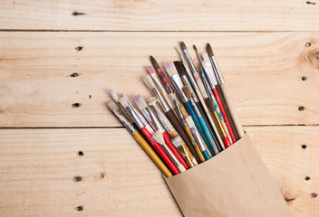 Fototapeta premium Paints, brushes and palette on the white wood background. The workplace of the artist. Banner for school