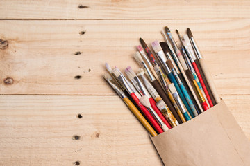 Paints, brushes and palette on the white wood background. The workplace of the artist. Banner for school