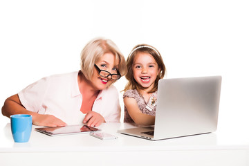 Grandmother and granddaughter uses laptop together and smiling on white background
