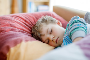 Obraz na płótnie Canvas Little sad preschool kid boy sleeping. Tired schoolchild resting after school classes.