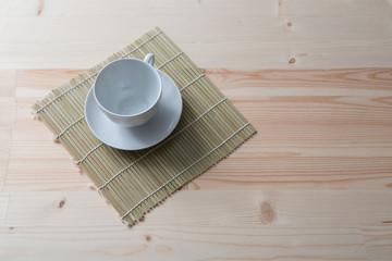 one pure white ceramic Cup and saucer stands on a wooden table