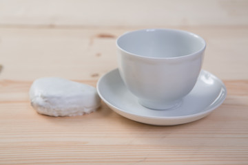 one pure white ceramic Cup and saucer and gingerbread stands on a wooden table