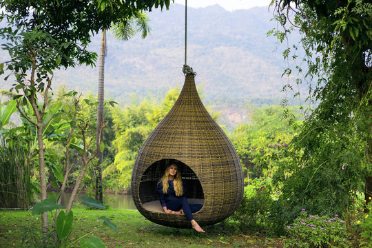 Scenic  view pf green forest with natural  hanging wicker swing in the drop shape design. Nice stuff for garden, park, patio and other outdoor places for recreation