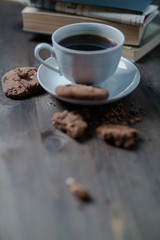 coffee Cup and cookies are next to the stack of books