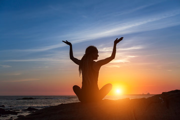 Yoga silhouette. Meditation woman on the ocean during beautiful sunset. Fitness and healthy lifestyle.