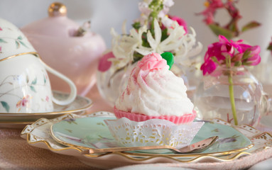 Obraz na płótnie Canvas High tea cupcake with pink icing and tea cup