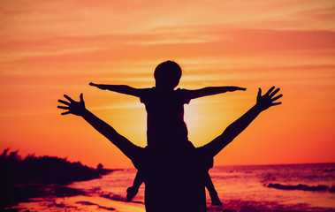 father and little son play on sunset beach