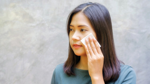 women use an absorbent cotton on her face.