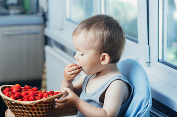 the child in the kitchen eating strawberries