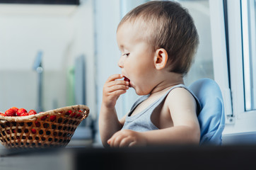 the child in the kitchen eating strawberries