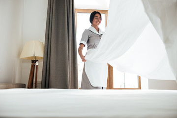 Hotel maid changing bed sheet - obrazy, fototapety, plakaty