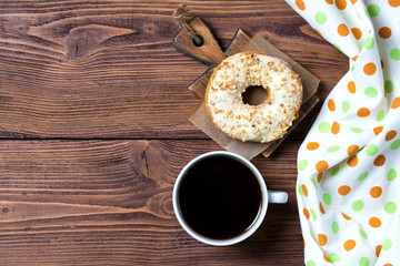 Donut with nuts and cup of coffee, wooden background, top view
