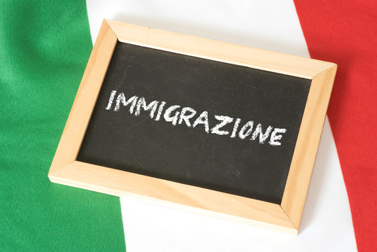 Italienische Flagge und eine Kreidetafel mit dem italienischen Wort für Zuwanderung