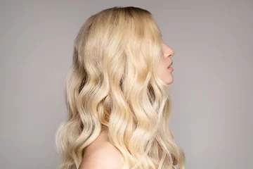 Photo sur Plexiglas Salon de coiffure Portrait Of A Beautiful Young Blond Woman With Long Wavy Hair.