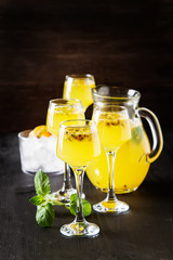 Alcoholic cocktail with fresh passion fruit with mint and ice. Dark wood background.