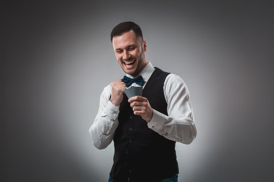 Young man in shirt and waistcoat watch his poker cards, studio shot
