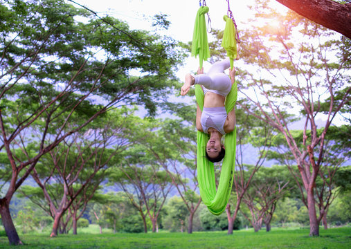 Young Asian Woman Aerial Yoga Fitness Practice Outdoor On The Tree Forest