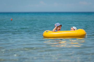Brother and sister sitting in inflatable boat in the sea