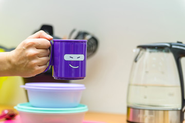 Hand holds plastic cup with smiling face